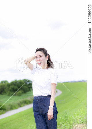 A woman strolling through a grassland or riverbank. A woman strolling through a grassland or riverbank. 142396603
