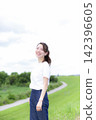 A woman strolling through a grassland or riverbank. 142396605