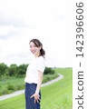 A woman strolling through a grassland or riverbank. 142396606