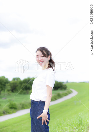 A woman strolling through a grassland or riverbank. A woman strolling through a grassland or riverbank. 142396606