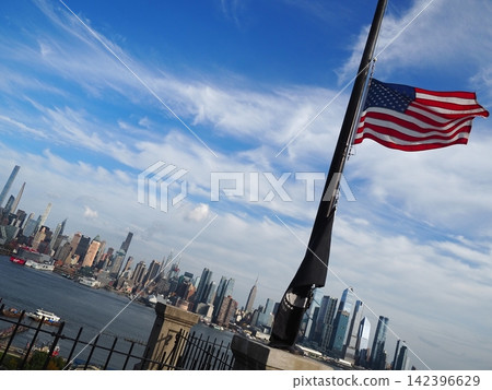 New Jersey, USA: Manhattan's skyscrapers and the American flag fluttering in the wind, viewed across the Hudson River. New Jersey, USA: Manhattan's skyscrapers and the American flag fluttering in the wind, viewed across the Hudson River. 142396629