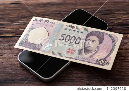 一張5000日元鈔票和一部智慧型手機 142397618