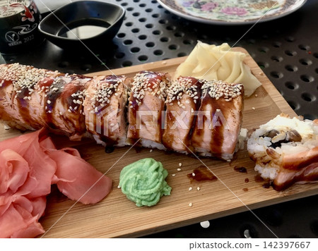 Seared salmon sushi roll served on a wooden board Seared salmon sushi roll served on a wooden board 142397667