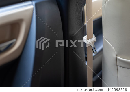 Close up of beige seat belt hanging beside car seat inside modern vehicle highlighting passenger restraint equipment automotive interior road safety Close up of beige seat belt hanging beside car seat inside modern vehicle highlighting passenger restraint equipment automotive interior road safety 142398828