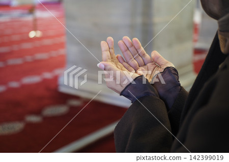 young woman praying with hands raised inside a mosque during worship young woman praying with hands raised inside a mosque during worship 142399019
