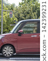 A red car driving across a pedestrian crossing 142399231