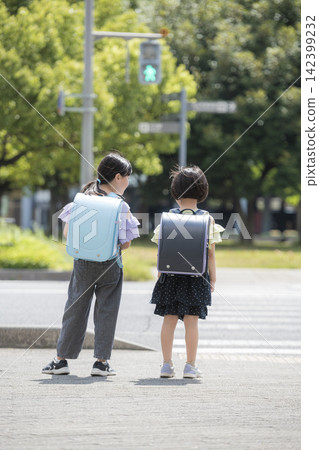 Children in school backpacks waiting in front of a crosswalk. 142399232