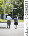 The backs of children in school backpacks crossing a pedestrian crossing. 142399233