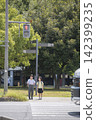 Children waiting at a crosswalk and cars driving by. 142399235