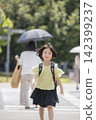 A young elementary school girl walking along her school route with her backpack on. 142399237
