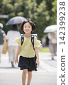 Elementary school students, wearing their school bags, run along their school route with smiles on their faces. 142399238