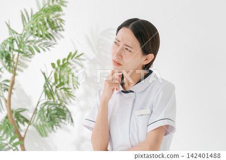 一位身穿白大褂、表情憂慮的女子。 一位身穿白大褂、表情憂慮的女子。 142401488