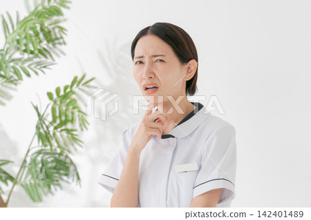 一位身穿白大褂、表情憂慮的女子。 一位身穿白大褂、表情憂慮的女子。 142401489