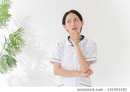 一位身穿白大褂、表情憂慮的女子。 一位身穿白大褂、表情憂慮的女子。 142401492