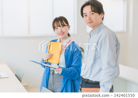 辦公室場景，一名女員工手持筆記本和寫字板，面帶微笑，直視鏡頭。 142401550