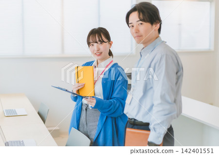 男女員工之間的商務溝通,他們面帶微笑,直視鏡頭。 男女員工之間的商務溝通,他們面帶微笑,直視鏡頭。 142401551