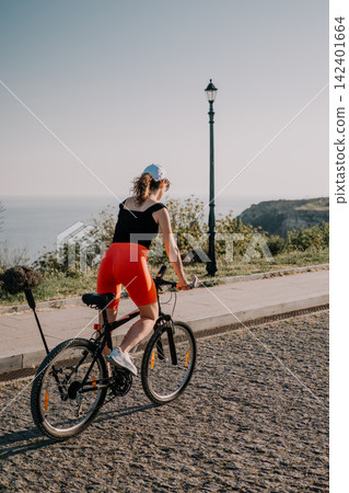 Cycling woman bicycle, young female riding bike on coastal path during sunny day while enjoying outdoor exercise in nature with freedom Cycling woman bicycle, young female riding bike on coastal path during sunny day while enjoying outdoor exercise in nature with freedom 142401664