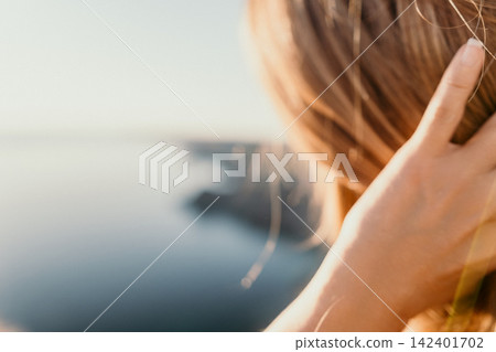 Woman hair sea person touching her long blonde hair while overlooking the ocean from a coastal cliff during a serene golden hour sunset Woman hair sea person touching her long blonde hair while overlooking the ocean from a coastal cliff during a serene golden hour sunset 142401702