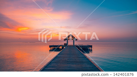 Breathtaking wooden jetty leading glowing pastel dusk calm azure Maldives lagoon warm reflected sky. Luxury travel honeymoon paradise scenic. Exotic getaway wall art decor Breathtaking wooden jetty leading glowing pastel dusk calm azure Maldives lagoon warm reflected sky. Luxury travel honeymoon paradise scenic. Exotic getaway wall art decor 142401876