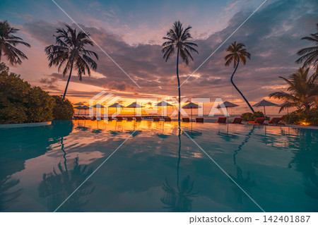 Romantic beach loungers thatched umbrellas silhouetted palms glowing sunset calm tropical lagoon reflection. Luxury honeymoon travel paradise scenic. Exotic couples getaway wall art decor Romantic beach loungers thatched umbrellas silhouetted palms glowing sunset calm tropical lagoon reflection. Luxury honeymoon travel paradise scenic. Exotic couples getaway wall art decor 142401887