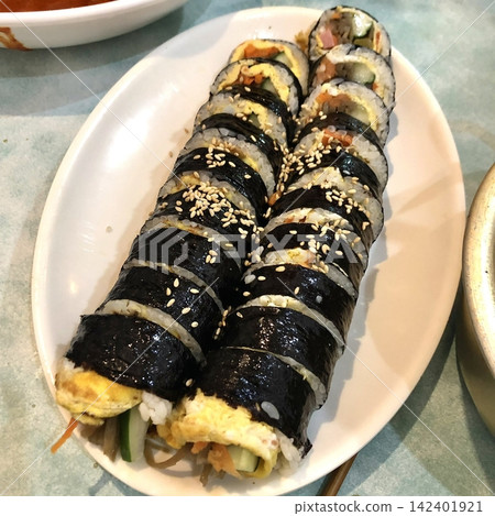 Delicious kimbap rolls filled with fresh vegetables, seasoned rice, and savory proteins, all wrapped in crisp seaweed. A perfect combination of flavor and texture in every bite. Delicious kimbap rolls filled with fresh vegetables, seasoned rice, and savory proteins, all wrapped in crisp seaweed. A perfect combination of flavor and texture in every bite. 142401921