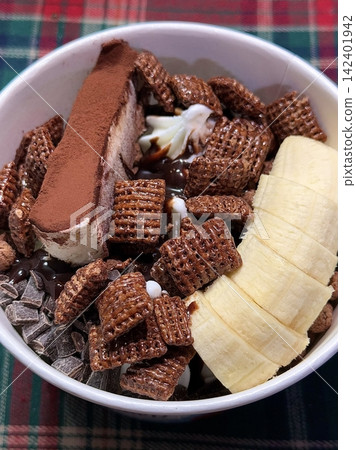 Swirled yogurt ice cream dessert served in a cup, smooth creamy texture with glossy surface, topped with fresh fruit pieces, highlighting its refreshing and inviting appearance in detail 142401942
