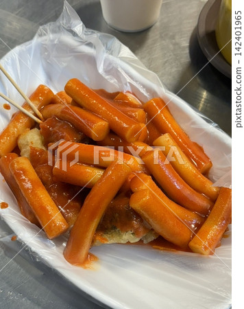 Spicy Korean tteokbokki with chewy rice cakes in a vibrant red sauce, topped with sesame seeds and green onions. A popular street food known for its addictive flavor and satisfying texture. Spicy Korean tteokbokki with chewy rice cakes in a vibrant red sauce, topped with sesame seeds and green onions. A popular street food known for its addictive flavor and satisfying texture. 142401965