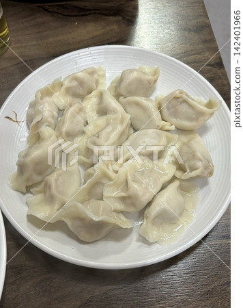 Steamed or fried mandu dumplings served alongside fermented kimchi, creating a classic Korean pairing that combines savory, tender dumplings with spicy, tangy, and flavorful fermented vegetables 142401966