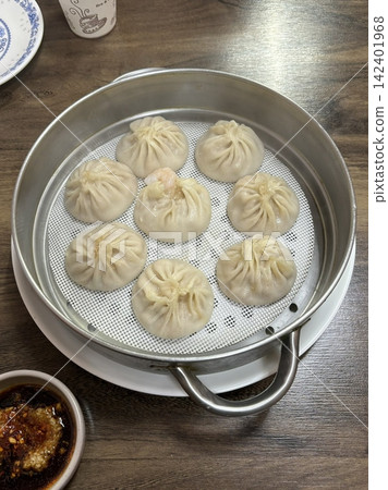 Steamed or fried mandu dumplings served alongside fermented kimchi, creating a classic Korean pairing that combines savory, tender dumplings with spicy, tangy, and flavorful fermented vegetables 142401968