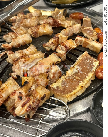 Grilled samgyeopsal, thick slices of pork belly with a perfect balance of crispy edges and tender meat. Served with lettuce, garlic, and dipping sauces for a classic Korean barbecue experience. 142402009