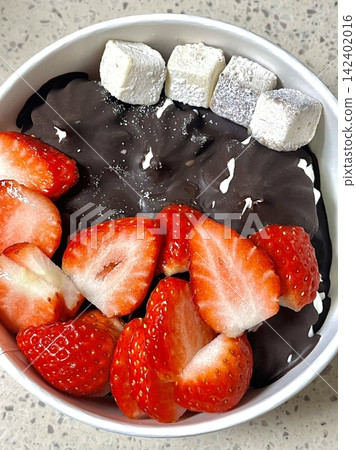 Swirled yogurt ice cream dessert served in a cup, smooth creamy texture with glossy surface, topped with fresh fruit pieces, highlighting its refreshing and inviting appearance in detail Swirled yogurt ice cream dessert served in a cup, smooth creamy texture with glossy surface, topped with fresh fruit pieces, highlighting its refreshing and inviting appearance in detail 142402016