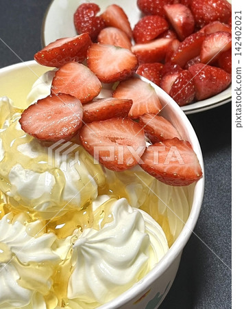 Swirled yogurt ice cream dessert served in a cup, smooth creamy texture with glossy surface, topped with fresh fruit pieces, highlighting its refreshing and inviting appearance in detail Swirled yogurt ice cream dessert served in a cup, smooth creamy texture with glossy surface, topped with fresh fruit pieces, highlighting its refreshing and inviting appearance in detail 142402021