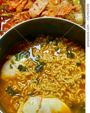 A steaming bowl of ramyeon with chewy noodles, rich and spicy broth, and flavorful toppings like green onions, egg, and vegetables. A quick and satisfying comfort food favorite. 142402036