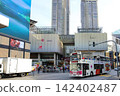 City street with buses tall buildings and people walking 142402487
