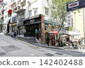 City street with shops and people walking on sidewalk 142402488