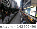 City street with tall buildings cars and pedestrians 142402490