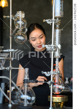 Asian Female Barista Operating Specialty Siphon Coffee Brewing Equipment at Modern Cafe Bar Asian Female Barista Operating Specialty Siphon Coffee Brewing Equipment at Modern Cafe Bar 142402536