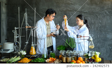 Two Asian Scientists in Lab Coats Analyzing Herbal Extracts with Laboratory Glassware and Natural Ingredients Two Asian Scientists in Lab Coats Analyzing Herbal Extracts with Laboratory Glassware and Natural Ingredients 142402573