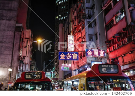 Night city street with colorful neon signs and buses Night city street with colorful neon signs and buses 142402709