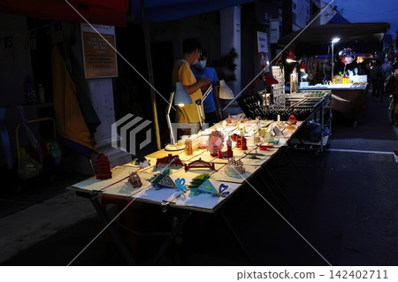 Night market food stall with illuminated dishes and people Night market food stall with illuminated dishes and people 142402711