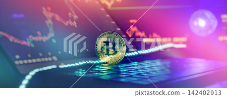Bitcoin cryptocurrency coin on laptop keyboard with financial stock market trading chart background in neon light. 142402913