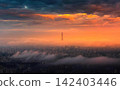Sunset sky with vibrant orange and dark clouds over city 142403446