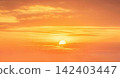 Sunset with orange sky and glowing sun over clouds 142403447