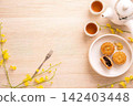 Sweet muffins on a white plate with tea cups and yellow flowers 142403448