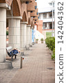 A man resting while lying on a park bench. 142404362