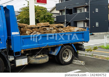 一輛裝滿混凝土碎塊的自卸卡車停在便利商店前。 一輛裝滿混凝土碎塊的自卸卡車停在便利商店前。 142404752