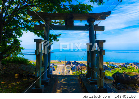 透過鳥居眺望蔚藍的大海和城鎮景色。 透過鳥居眺望蔚藍的大海和城鎮景色。 142405196