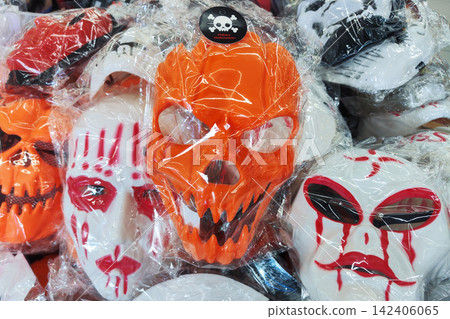 scary plastic Halloween masks in clear packaging on a retail store display. Orange skull and bloody white masks for trick-or-treat party costumes. scary plastic Halloween masks in clear packaging on a retail store display. Orange skull and bloody white masks for trick-or-treat party costumes. 142406065