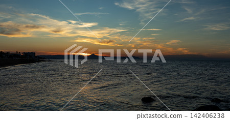 Golden sunset over ocean with mountain silhouettes in the background Golden sunset over ocean with mountain silhouettes in the background 142406238