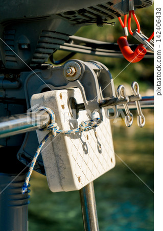 Detailed view of an outboard motor clamp secured on a sailboat stern rail. Concept of engineering, reliability, maintenance and marine safety Detailed view of an outboard motor clamp secured on a sailboat stern rail. Concept of engineering, reliability, maintenance and marine safety 142406438